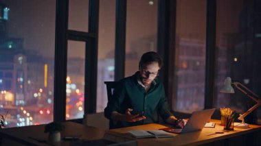 Karanlık ofis panoramik penceresinde cep telefonuyla konuşan iş analisti. Sakallı danışman, not defterine akıllı telefon notları yazmaktan bahsediyor. Gülümseyen işadamı gece ofisinden cep telefonunu arıyor..