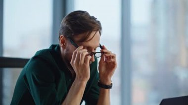 Modern iş yerinde gözlük çıkarmayı düşünen düşünceli bir proje. Sakallı işadamı, ofis çalışma alanında oturarak yeni fikirlere kafa yoruyor. Profesyonel girişimci planlama stratejisi.