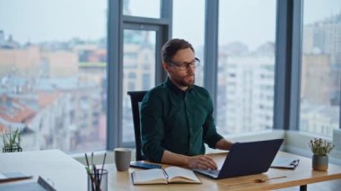 Şirket yöneticisi, çağdaş iş yerinde proje tarama dizüstü bilgisayarı üzerinde çalışıyor. Sakallı işadamı, özet defterine veri yazma raporunu kontrol ediyor. Profesyonel çalışan planlama stratejisi.