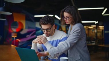 Profesyonel kadın kreatif ajans salonunda projeyi tartışıyor. Modern iş yerinde laptopla iş birliği yapan odaklanmış iş arkadaşları. Şirket toplantısında ciddi takım çalışması.