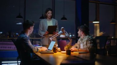 Karanlık Panoramik Pencere Ofisi 'nde yardımcı bayan patron. Geç kalmış meslektaşlarım açık alanda bilgisayar çalışıyor. İki erkek yönetici akşam iş yerinde dizüstü bilgisayar kullanıyor. Son teslim tarihi olan gece iş arkadaşları