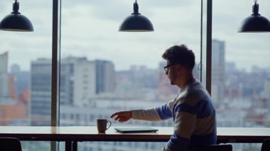 Şehir manzaralı işyerinde kahve yudumlayan dalgın bir acemi. Mesafeli müdür Panorama Pencere Salonu 'nda sıcak içecek içiyor. Serbest çalışan adam modern cam duvarların içini dinlendiriyor. 