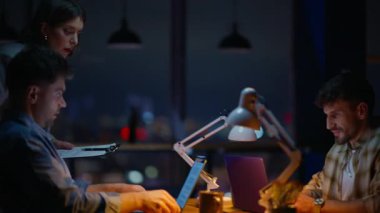 Geç saatlerde ofiste danışmanlık yapan ciddi bir danışman. Bilgisayara bakan bir kadın meslektaşlarına tavsiyelerde bulunuyor. Yaratıcı genç yöneticiler içeride sorun çözme konusunda tartışıyorlar