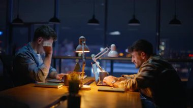 Ofis odasında geç saatlere kadar çalışan yorgun serbest çalışanlar. Esmer adam kollarını açmış yorgun hissediyordu. Çok çalışan meslektaşlar, yaratıcı iç işyerlerinde iletişim kurma tarihine hazırlanıyorlar.