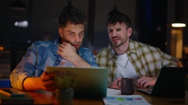 Geç saate kadar çalışan iş arkadaşları dizüstü bilgisayara bakıp akşam iş yerinde projeyi tartışıyorlar. Fazla mesai müfettişleri bilgisayar masasında iletişim kuruyor. Tasarımcılar birlikte konuşuyor. Karanlık odayı analiz ediyorlar. 