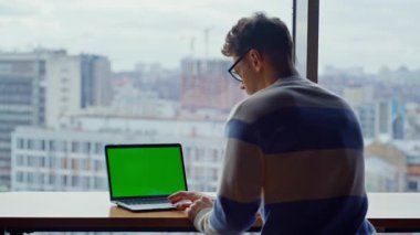 Panoramik iş yerinde yeşil ekran bilgisayar kullanarak çalışıyor. Şehir ofisindeki başlangıç modelleme pc cihazına odaklanmış. Masadaki Chromakey Dijital Alet 'te çalışan gözlüklü adam. 