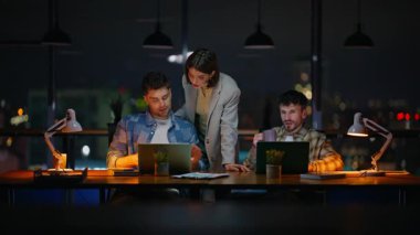 Karanlık panoramik pencere ofisindeki danışman kadın yöneticiler. Birlikte çalışan geç dönem bilgisayarları. Patron astları akşam işyerinde dizüstü bilgisayar arıyorlar. Gece denetçilerinin teslim tarihi var.