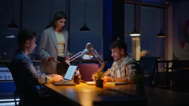 Kadın patron, cam duvarların önünde çalışan işçileri tartışıyor. Stresli bayan teslim tarihinden memnun değil. Duygusal olarak el kol hareketi yapıyor. İki adam dizüstü bilgisayarda çalışıyor. Akşam ofisindeki sinirli patronu dinliyorlar.