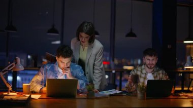 Gece ofisi atmosferde çalışıyor. Akşamları görev çözen üç denetçi. Sanat yönetmeni kadın grafik tasarımcılarının karanlık panoramik konuşmalarına yardım ediyor. İş birliği yaparken takım arkadaşlarıyla konuşuyorlar.