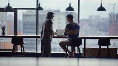 İş çifti, şirket binasında çay bardaklarını tokuşturup şehir manzarası hakkında konuşuyor. İki işçi panoramik pencerede kahve içerek dinlenme odasını tartışıyor. İş arkadaşları birlikte çalışıyor. 