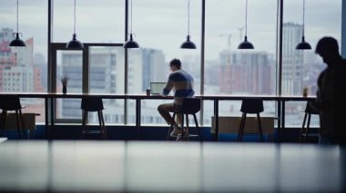 Şehir merkezinde laptopla sıcak içecek yudumlayan bir iş arkadaşı. Odaklanmış işçi kasvetli şehir manzaralı e-posta yolluyor. Şirket yöneticisi kahve içiyor açık alanda bilgisayarla oturuyor.