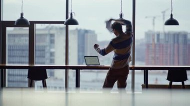 Heyecanlı girişimci şehir pencereleri yakınında iyi haberleri kutlayan dizüstü bilgisayarı kontrol ediyor. Neşeli menajer terfi alıyor, belgeleri mutlulukla atıyor. Neşeli iş adamı heyecanlanıyor. Çevrimiçi başarı
