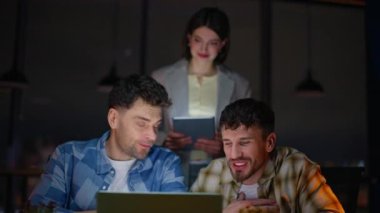 İş arkadaşları akşam çalışma alanında bilgisayardan bilgisayara sesleniyor. Mutlu iş kadını ve iki yönetici gece kabinesinde el kol hareketi yapıyorlar. İş arkadaşları müşteriyle dostça sanal toplantı yapıyor.