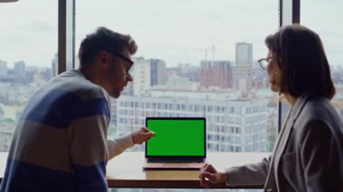 İş arkadaşları büyük pencereli ofislere bilgisayar doğrultuyor. Krom anahtar dizüstü bilgisayarla çalışan iki ortak projeyi tartışıyor. Erkek kadın takım arkadaşları açık alanda yeşil ekran izliyorlar