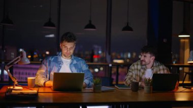 Karanlık kabinede birlikte çalışan iş arkadaşları. Akşam ofislerinde dizüstü bilgisayar kullanan profesyoneller. Geç saatlerde iş yerinde görüşlerini paylaşan bilgisayarlar yazan iki geliştirici
