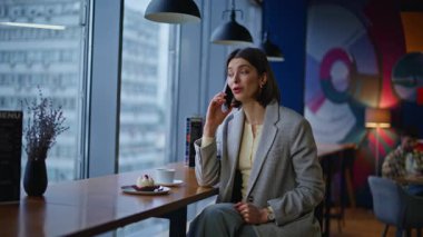Cep telefonuyla gülen zarif katılımcı kafenin yakın çekimlerinde arkadaşça iletişimin keyfini çıkarıyor. Küçük restoran tezgahında oturan mutlu kadın akıllı telefonu arıyor. Esmer yönetici içeride cep telefonu konuşuyor.