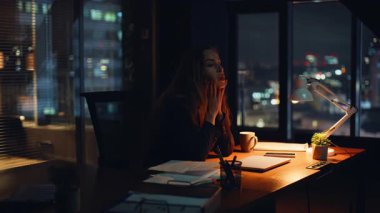 Karanlık modern ofis iç çekimlerinde fazla mesai yapmaktan yorgun düşmüş bir çalışan. Yorgun yönetici gece vardiyasında yalnız kalıyor. Kurumsal çalışma alanındaki gece masasında yorgun düşmüş profesyonel dinlenme solosu.