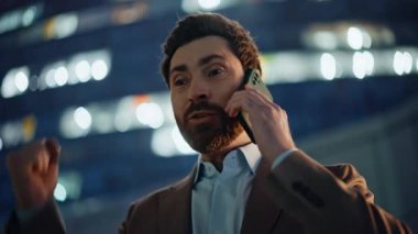 Memnuniyetle girişimci konuşan mobil cihaz Alacakaranlık Portresi 'nde duruyor. Neşeli yönetici, mutluluğu ifade eden olumlu bir güncelleme alıyor. Kendinden geçmiş patron telefon konuşmasında başarıdan zevk alıyor.