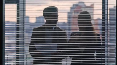 Kendine güvenen iş ortakları, özel atmosfer sohbetleri yakın çekim. İki rahat iş arkadaşı büyük vitrin ofisinde duran kağıtları inceliyor. Siluet meslektaşları sözleşmeyi tartışıyorlar