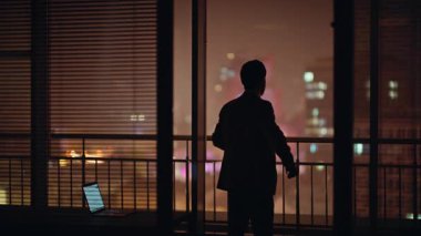 Şehir manzarası panoramik ofis arka görüşünde sorunlu profesyonel siluet düşünme sorunu. Takım elbiseli adam tek başına pencereden bakıyor. Endişeli yönetici karanlık işyerinde gergin hissediyor