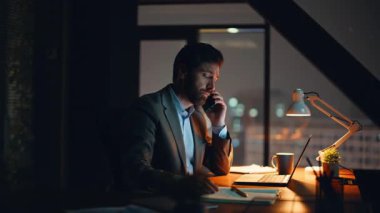 Hayal kırıklığına uğramış yönetici geç saatte iş yerinde telefonla arıyor. Yakın plan. Endişeli patron telefon konuşmasından şikayetçi, iş sonuçlarından memnun değil. Üzgün yönetmen içeride astıyla konuşuyor.