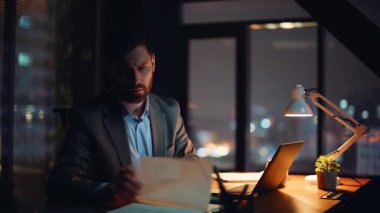 Gece geç saatlerde karanlık çalışma alanında girişimci planlama projesi. Gece ofisindeki dizüstü bilgisayarını kullanan çalışkan bir iş adamı gibi görün. Yorgun yönetici fazla mesai yaparak bilgisayar kapağını kapatıyor