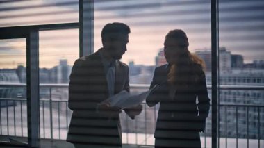 Kızgın yönetmen tartışan sekreter, büyük pencerenin önünde yakın plan. Stresli işadamı elinde saldırgan bir şekilde el kol hareketi yapan kağıtlar tutuyor. Sinirli iş kadını iş ortağıyla çelişen raporlar atıyor.