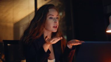 Öfkeli yönetici, modern akşam çalışma alanının içinde sanal seans sırasında bağırıyor. Web kamerası tartışmasına dökümanları gösteren hayal kırıklığına uğramış bir gece çalışanı. Dijital toplantıda hayal kırıklığını ifade eden kadın