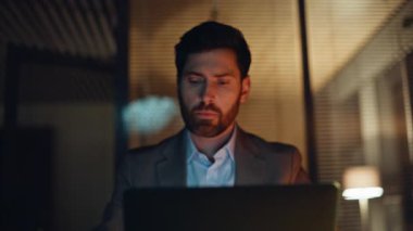 Mutlu kazanan dizüstü bilgisayara bakıyor ve gece ofisindeki iş başarısını kutluyor. Heyecanlı iş adamı projenin başarısından duygusal olarak zevk alıyor. Büyük sevinçle bilgisayar başında harika haberler okuyor.