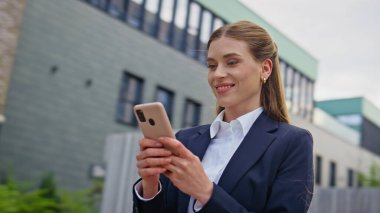 Olumlu yönetmen akıllı telefondan Business Street 'in kapanış sahnesinde mesaj yazıyor. Gülümseyen iş kadını şehir merkezindeki telefon mesajlarını okuyor. Mutlu kadın cep telefonuyla sosyal medyada geziniyor..