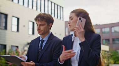 Kadın patron cep telefonuyla konuşuyor. Şehir merkezindeki erkek sekreterle yürüyor. İki şirket ortağı şehir merkezinde iş gezisini tartışıyor. İş adamı, iş kadınını aramak için gerekli belgeleri gösteriyor..