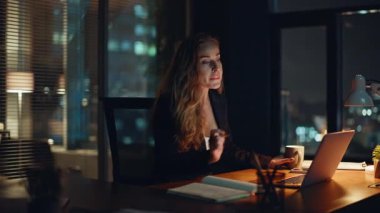 Gece işkadını kahve yudumlarken ofis masasına yakın çekim yapıyor. Genç, kendine güvenen bir şirket çalışanı elinde fincanla işyerinde içecek tatmanın tadını çıkarıyor. Ciddi çekici bir iş kadını dizüstü bilgisayarı. 