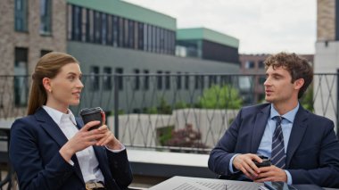 Gülümseyen meslektaşlar açık hava kafeteryasında kahvelerini yudumluyorlar. Rahat iş arkadaşları birlikte içki içerek sohbet ediyorlar. Gayri resmi iş molalarında kendine güvenen ortaklar bağlanır.