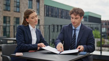 Çatıdaki iş yerindeki şirket toplantısında evrakları gözden geçiren odaklanmış ortaklar. İş anlaşması imzalayan profesyoneller el sıkışıyor. İşadamları işbirliği anlaşmasını sonuçlandırdı.