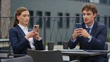 İş yerindeki işadamları, kapalı kafeteryadaki akıllı telefonlara odaklandılar. Takım elbiseli profesyoneller kafenin balkonunda mobil cihazlarla meşgul. İş mesajlaşmasına odaklanan meslektaşlar.