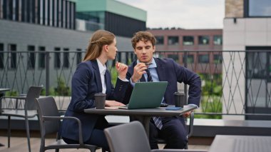 Profesyonel iş arkadaşları şehir kafesinin balkonunda dizüstü bilgisayar ararken beyin fırtınası yapıyorlar. Ciddi ortaklar proje üzerinde ortaklaşa strateji tartışıyor. İş arkadaşları restoran terasında takım çalışması yapıyor..