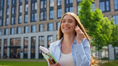 Akıllı telefondan konuşan mutlu öğrenci, güneşli bir sabahta çalışmaya devam ediyor. Gülümseyen iş kadını elinde defterlerle gezerken cep telefonunu arıyor. Neşeli kadın sokakta yürüyor, telefon konuşmasından keyif alıyor..