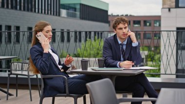 İş ortakları restoran terasını arıyor. Odaklanmış iş kadını dışarıda ciddi bir telefon görüşmesi yapıyor. Meslektaşlar iş görüşmelerini cep telefonlarıyla yapıyorlar..