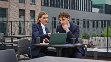 Dışarıdaki ofis masasında iş birliği yapan meslektaşlar. İş ortakları modern restoran terasında laptop verilerini tartışıyor. İş kadını profesyonel toplantıda takım çalışmasından zevk alıyor