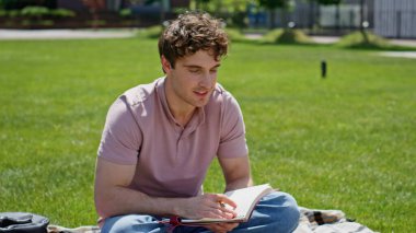 Çevrimiçi derste güneşli yeşil parkın yakınında oturan öğrenci selamı. Akıllı adam güzel çimlerde dizüstü bilgisayarla sanal konferansa başlıyor. Genç serbest yazar, uzak webinar dinliyor.