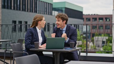 Açık hava toplantısındaki başarıyı kutlayan heyecanlı iş arkadaşları. Neşeli iş ortakları kafeterya terasında proje başarılarından duydukları heyecanı dile getirdiler. İş arkadaşları takım çalışması başarısını kutluyor.