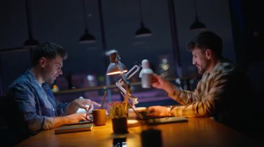 Modern panoramik kabinede dizüstü bilgisayarlar yazan geç kalmış iş arkadaşları. İki enerjik adam kahve içiyor ve akşamları açık alanda bilgisayar başında birlikte çalışıyorlar. Pozitif yöneticiler gece odasında konuşuyor.