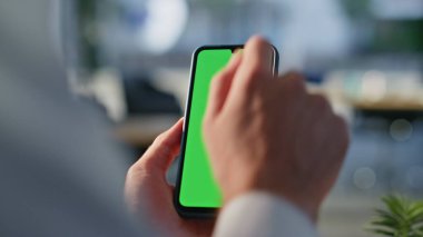 Modern çalışma alanında krom anahtarlı cep telefonu araklayan bir yönetici. Ofisteki yeşil ekranlı akıllı telefona dokunan tanınmamış iş adamı eli. Model telefondan iş e- postalarına bakan profesyonel bir adam..