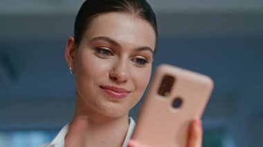 Neşeli kız cep telefonundan SMS okuyor. Evde akıllı telefondan sosyal medya içeriğini izlerken gülümseyen mutlu esmer. Çekici bir kadın cep telefonunda flört uygulamasına göz atıyor.