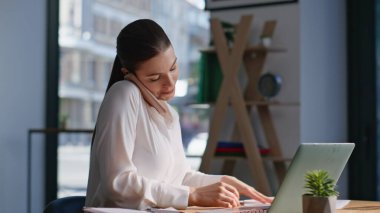 Serbest çalışan biri cep telefonunu arıyor. Dizüstü bilgisayarda çalışıyor. Çağdaş çalışma alanının yakın planında oturuyor. Çok yönlü gülümseyen iş kadını akıllı telefon konuşmalarıyla projeyi tartışıyor. Telefondan konuşan kendine güvenen bir bayan..