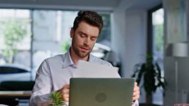 Modern çalışma alanına yakın oturan kağıtları analiz etmek başarılı bir başlangıçtı. Finans raporunu okuyan gülümseyen işadamı başarıyı hissediyor. Şirket ofisindeki mutlu muhasebeci sevindirici belgeler.