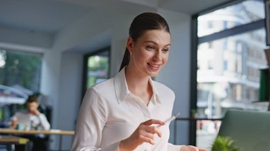 Bilgisayarlı web kamerasına proje belgelerini sunan bir kadın. Ofisteki açık alanda konuşan gülümseyen bayan. Uzak konferansta kağıtları tartışan mutlu iş kadını..