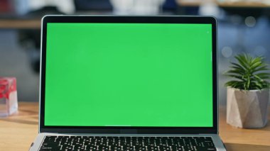 Chroma anahtar dizüstü bilgisayar modern şirket çalışma alanına yakın plan yerleştirildi. Yeşil ekran bilgisayar, ahşap ofis masasında profesyonel görevler için hazır. Boş işyerindeki iş akışını geliştiren işlevsel teknoloji.