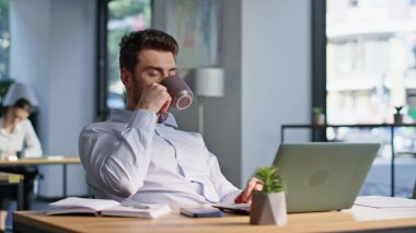 Rahat iş adamı, modern iş yerinde oturup çay içiyor. Sakin sakallı ofis müdürü sıcak kahveyi yudumlarken iş molası veriyor. Kendine güveni olan bir işçi, kariyerini düşünerek içkiyle dinleniyor.