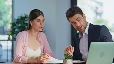 İşletme müdürü, şirket ofisinde proje detaylarını açıklayan bir kadına danışmanlık yapıyor. İş adamı danışmanı bayan dizüstü bilgisayar ekranı gösteriyor. Gülümseyen iş kadını belgeleri imzalıyor ve danışman elini sıkıyor.